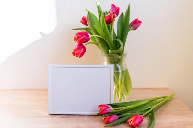 Portrait white picture frame mockup on wooden table Modern vase with tulipsScandinavian interior