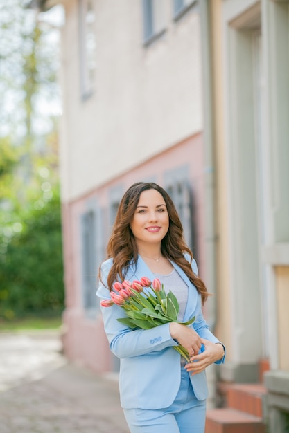 Portrait of a woman in a blue suit with a bouquet of tulips