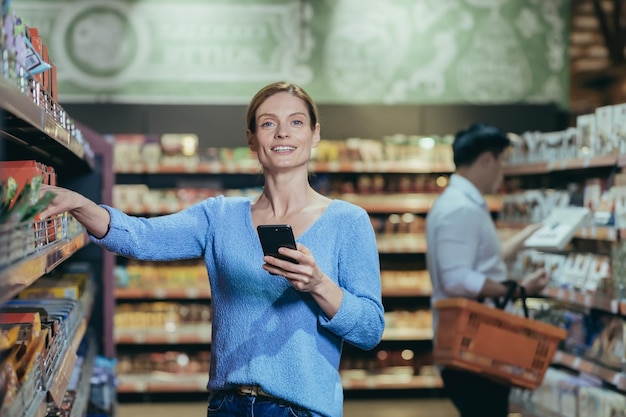 Portrait of a woman buyer in a supermarket in the grocery department a blonde housewife chooses