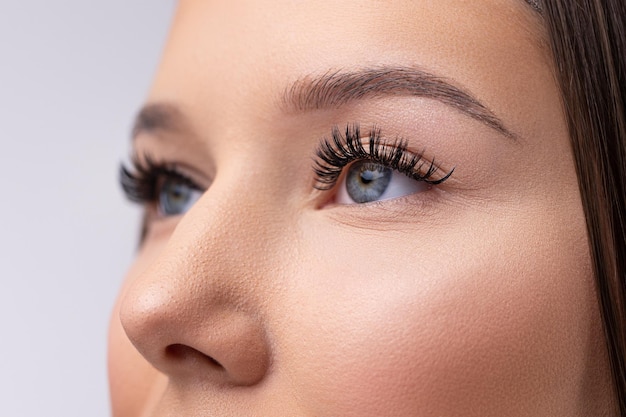 Portrait of woman face young beautiful girl with fresh soft skin combing long black eyelash