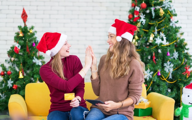 Portrait of woman and friend showing a blank credit card in christmas holidays, Christmas and New Year shopping on the Internet, payment by credit card.