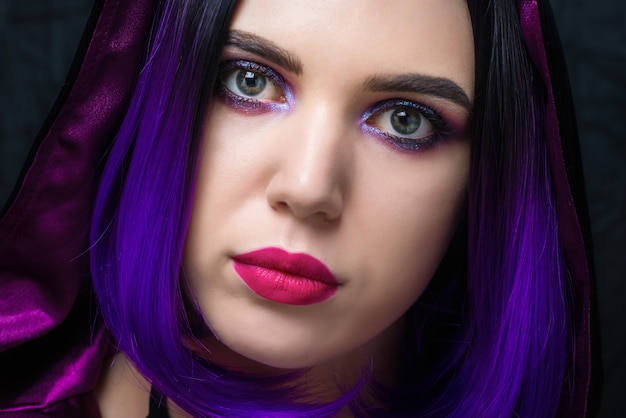 Portrait of woman in halloween costume with bright make up and purple hair