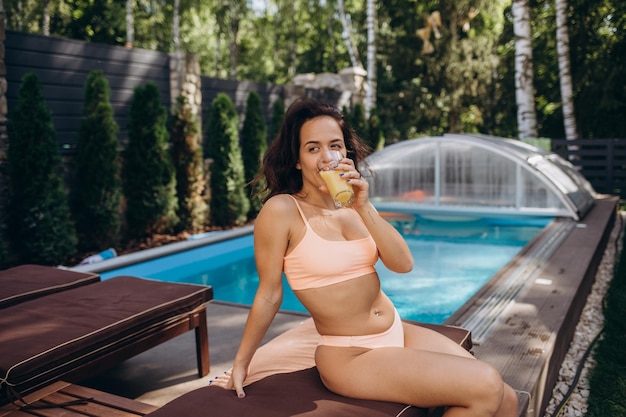 Portrait of woman hand enjoy holiday vacation with orange juice in swimming pool this image for outdoor and relaxation concept