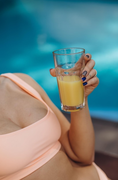 Portrait of woman hand enjoy holiday vacation with orange juice in swimming pool this image for outdoor and relaxation concept