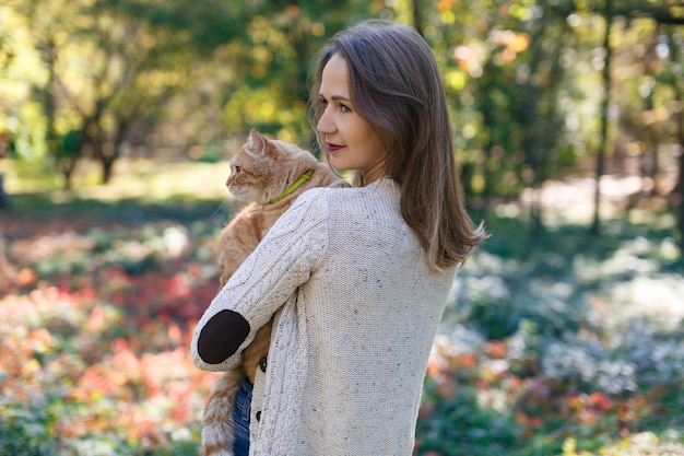 Portrait a woman holding big red fluffy cat on the nature happy girl and cute fluffy cat outdoors