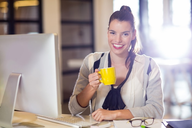 Portrait of woman holding coffee cup in office