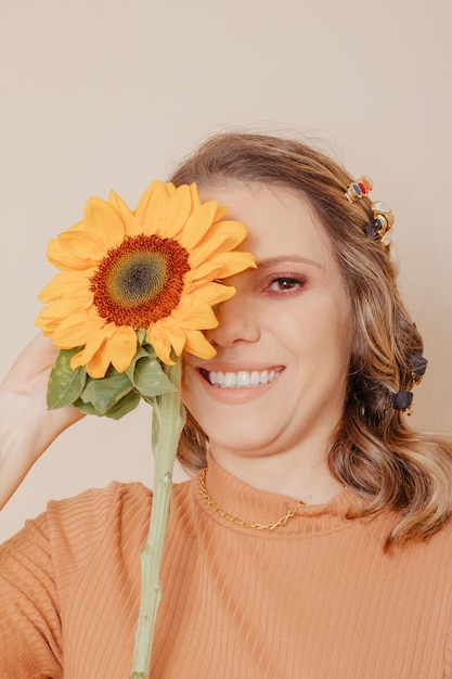 Portrait of woman holding a sunflower Woman with clipon hair accessories on cream background