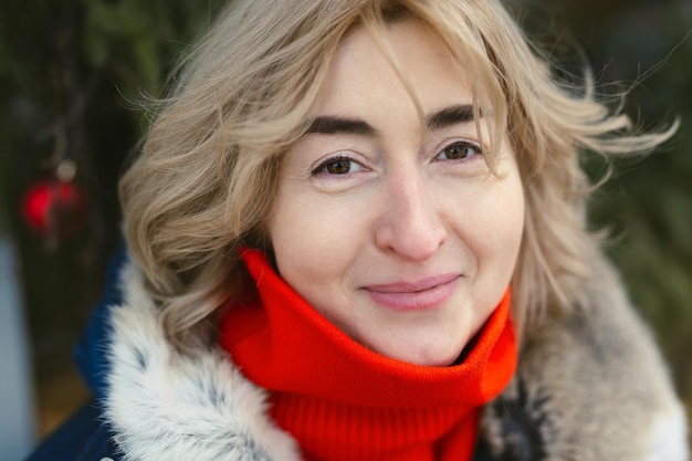 Portrait of a woman in a hood and a red scarf on a frosty day