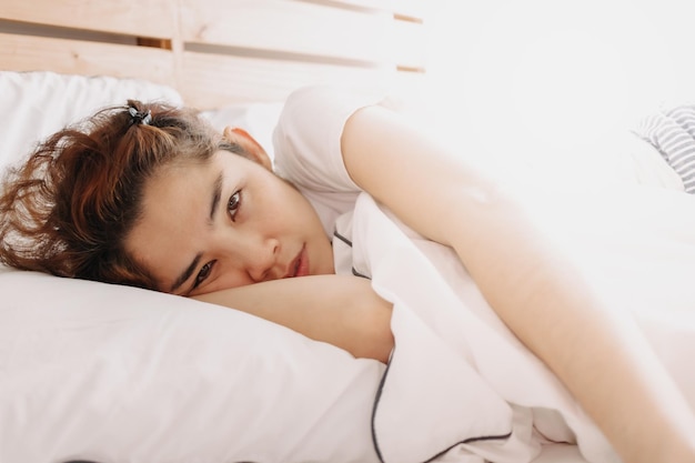 Portrait of woman lying on bed at home