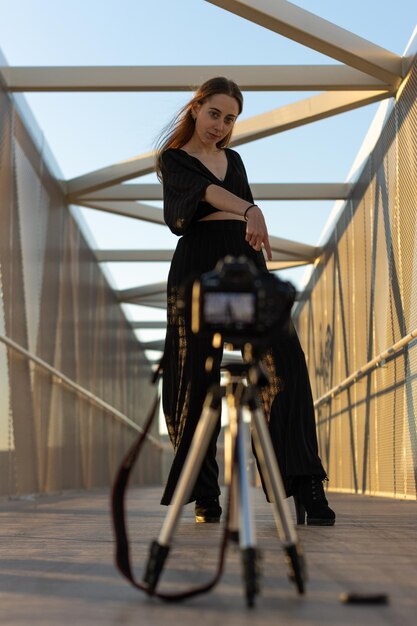 Portrait of woman modeling for a camera mounted on a tripod Woman on a bridge posing to a camera