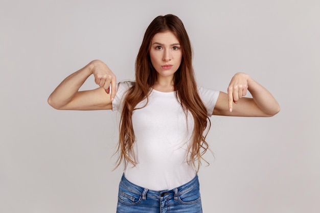 Portrait of woman pointing fingers down ordering and controlling demanding result immediately