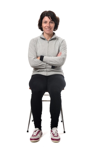 Portrait of a woman sitting on a chair in white background, arms crossed