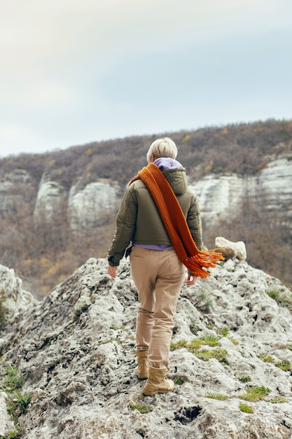 Portrait of a woman standing on a mountain in autumn in warm clothes knitted scarf