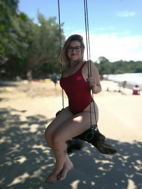 Photo portrait of woman in swimwear sitting on swing at beach