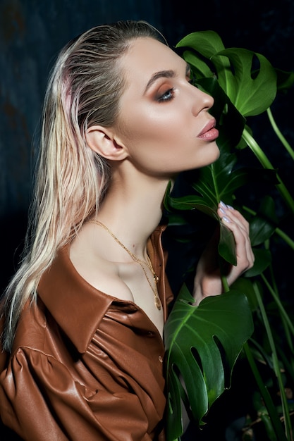 Portrait of a woman in tropical foliage. Wet hair, perfect figure and makeup