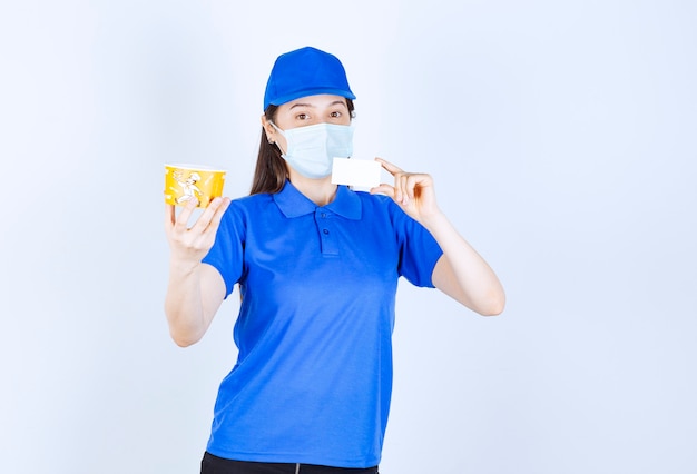 Portrait of woman in uniform and medical mask holding card