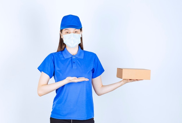 Portrait of woman in uniform and medical mask holding paper box