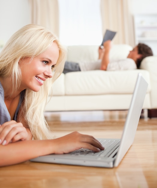 Portrait of a woman using a laptop while her husband is reading