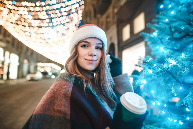 portrait woman wearing Santa hat holding cup of coffee