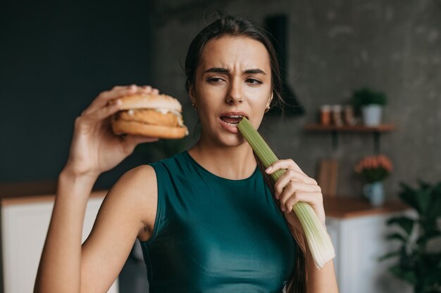 Portrait of a woman wearing sports clothes choosing vegetables instead burger Beautiful woman sportswear choosing food great design for any purposes