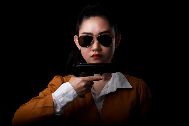 Portrait of woman wearing a yellow suit and holding pistol gun