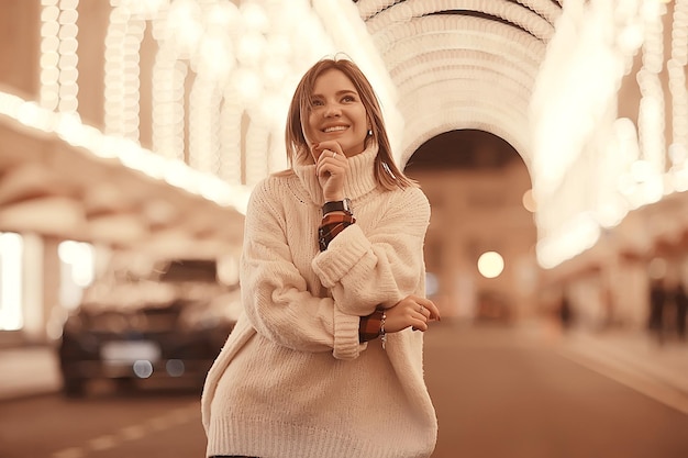 portrait of a woman white sweater winter, seasonal outside city walk in the evening city