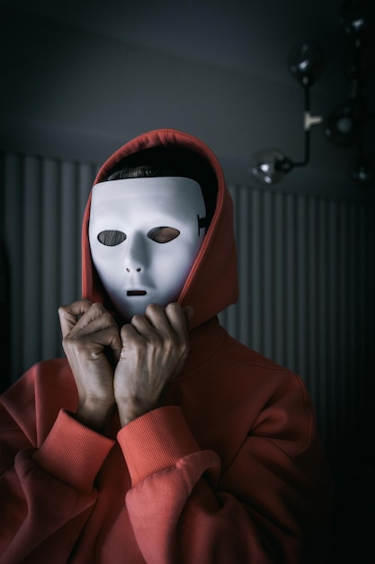 Portrait of woman in white theater mask and hood on black background Concept of mental disorders hypocrisy