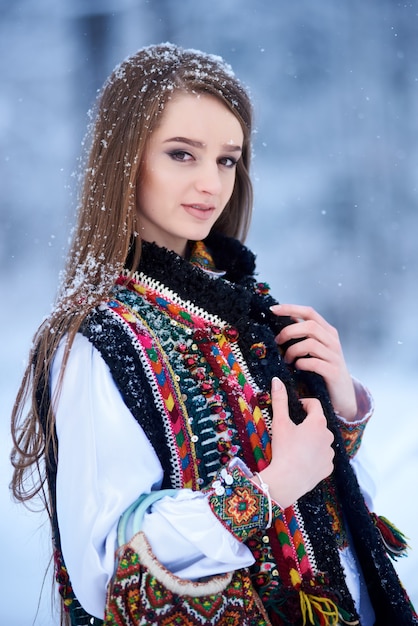 Portrait of woman on winter day on snowy landscape background