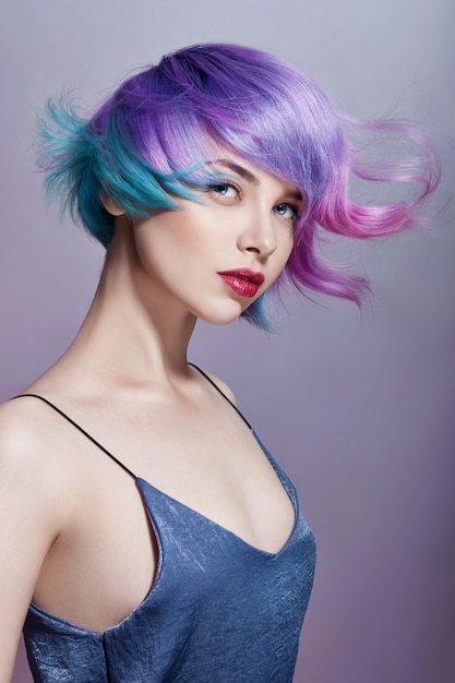 Portrait of a woman with bright colored flying hair, all shades of purple. Hair coloring, beautiful lips and makeup. Hair fluttering in the wind. Sexy girl with short hair