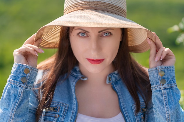 Portrait of woman with gray eyes looking at camera on blurred green natural background of forest