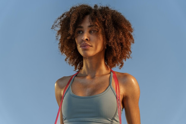 Portrait of woman with jump rope on studio background looking at side strength and motivation