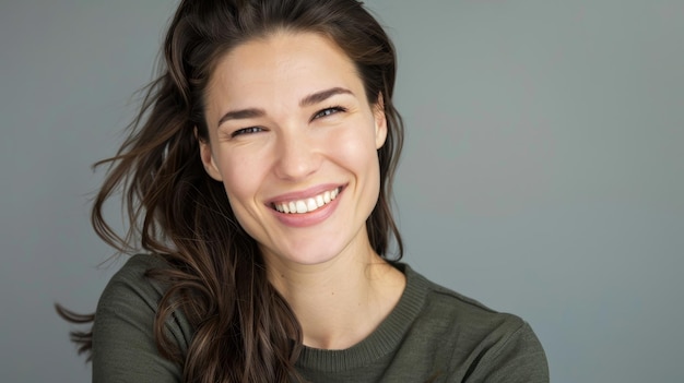 Portrait of a Woman With Long Brown Hair Smiling Against a Gray Background