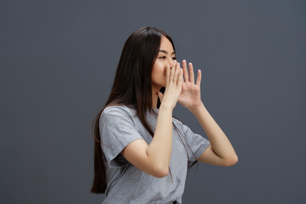 Portrait woman with long hair in a gray Tshirt gesturing with hands Gray background