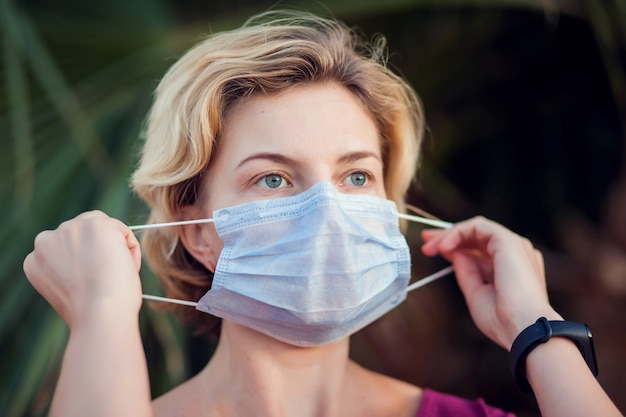 A portrait of woman with medical face mask outdoor. People, healthcare and medicine concept