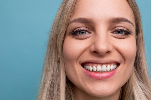 Portrait of a woman with a snowwhite hollywood smile and on a blue background