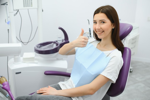 Portrait of a woman with toothy smile sitting at the dental chair at the dental office