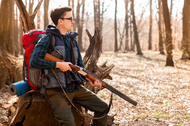 Portrait of yang hunter with a backpack and a gun on the forest