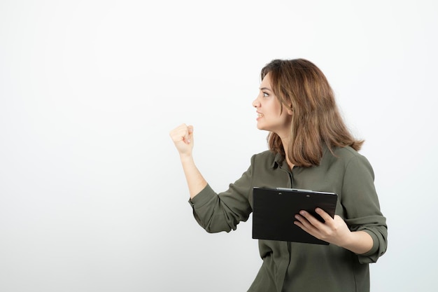 Portrait of young adorable woman with clipboard arguing with someone. High quality photo