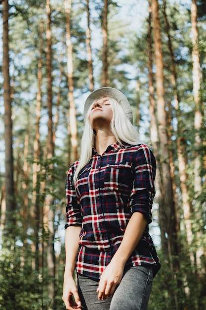 Photo portrait of young adult female in plaid shirt walking in the forest, selective focus