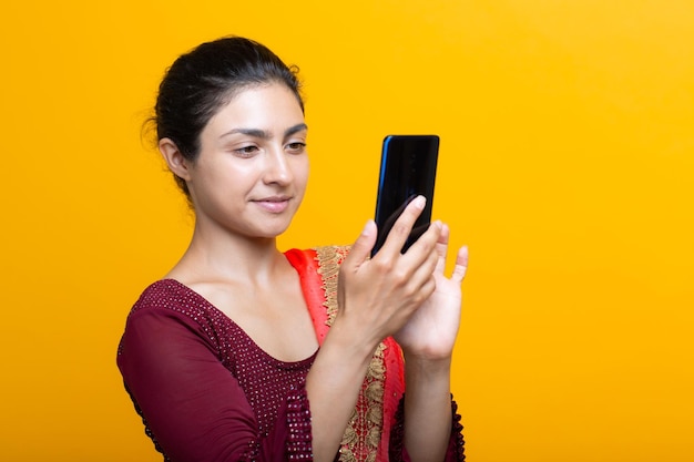 Portrait of young adult indian woman in sari with mobile phone