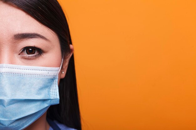 Portrait of young adult medical nurse wearing facemask against coronavirus on orange background. Healthcare hospital responsible worker wearing virus protection facemask.