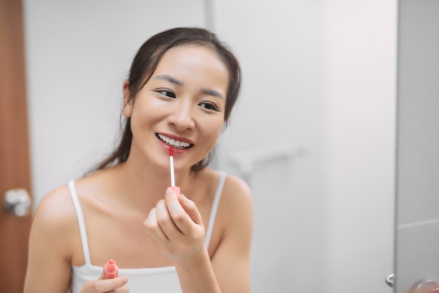 Portrait of a young adult woman applying makeup on her face