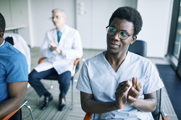 Portrait of young African-American doctor applauding at medical conference or seminar, copy space