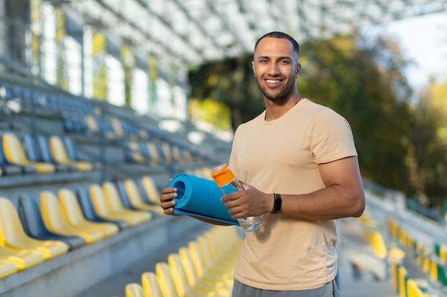 Portrait of a young african american male athlete coach standing in a stadium holds an exercise and