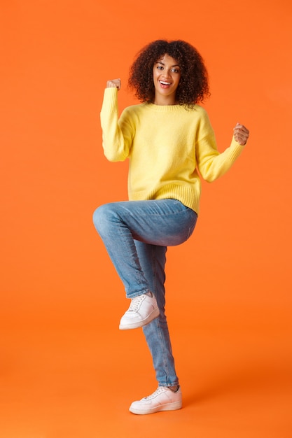 Portrait young African American woman showing gesture on orange