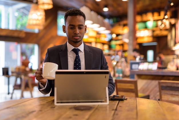 Portrait of young African businessman relaxing inside coffee shop