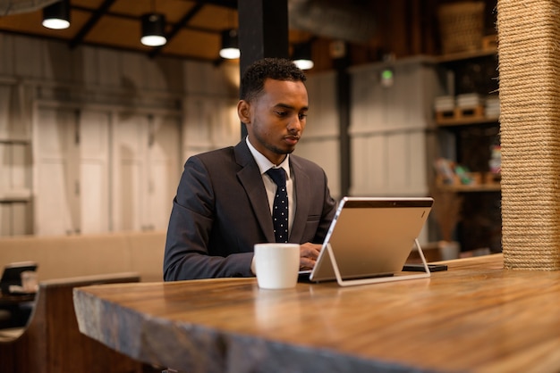 Portrait of young African businessman relaxing inside coffee shop