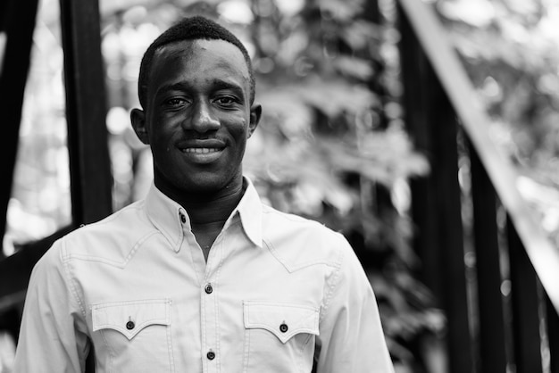 Portrait of young African businessman relaxing in the streets outdoors in black and white