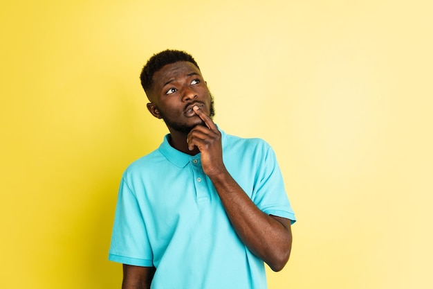 Portrait of young African man isolated over yellow studio background with copyspace