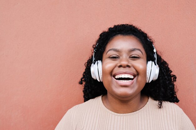 Portrait of young african woman listening music with headphones outdoors in the city